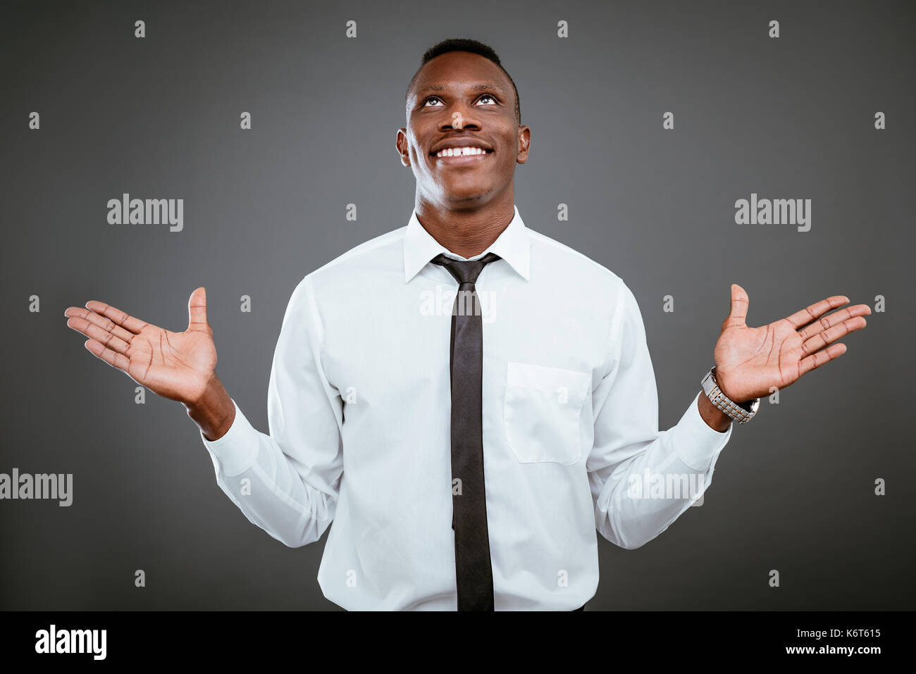 Happiness African businessman celebrating success with raised arms, looking up and praying god. Stock Photo