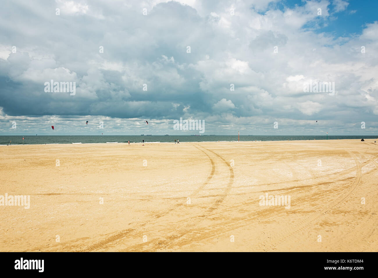 Kytesurfers on the beach of Scheveningen with in the background the seagoing ships at anchor waiting to enter the port of Rotterdam in The Netherlands Stock Photo