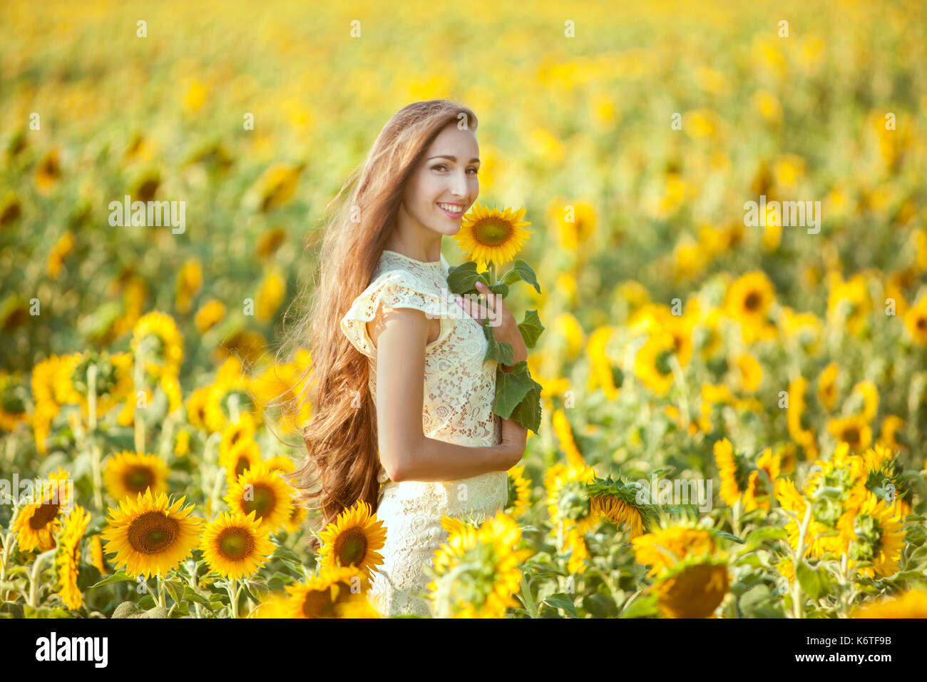 Woman with long hair stands in a field of sunflowers and smiles Stock ...