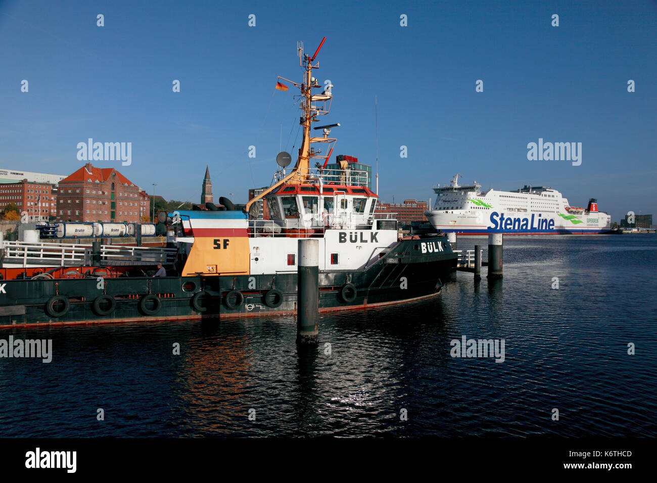 The tug boat, Bülk, moored in the port of Kiel with the Stena Line ferry Stena Germanica in the background. Stock Photo