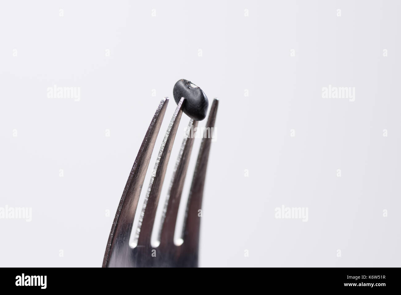 Food, Deutschland, Rheinland-Pfalz, Waldsee, Studio, September 13. Eine schwarze Bohne steckt vor weißem Hintergrund auf einer Gabel . Stock Photo