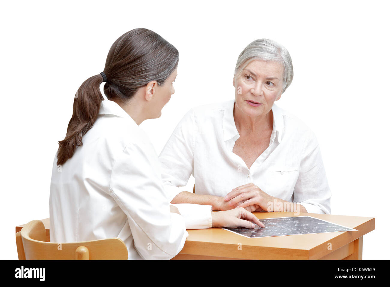 Female middle aged doctor showing her senior patient an ct scan of her head, isolated on white background Stock Photo