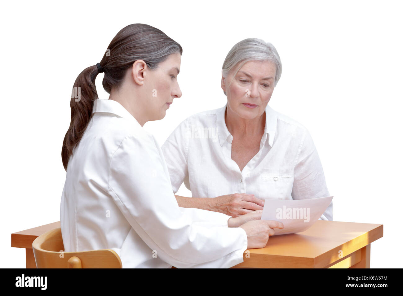 Female doctor showing her senior patient a paper bill or check, listing the costs of the medical treatment, isolated on white background Stock Photo