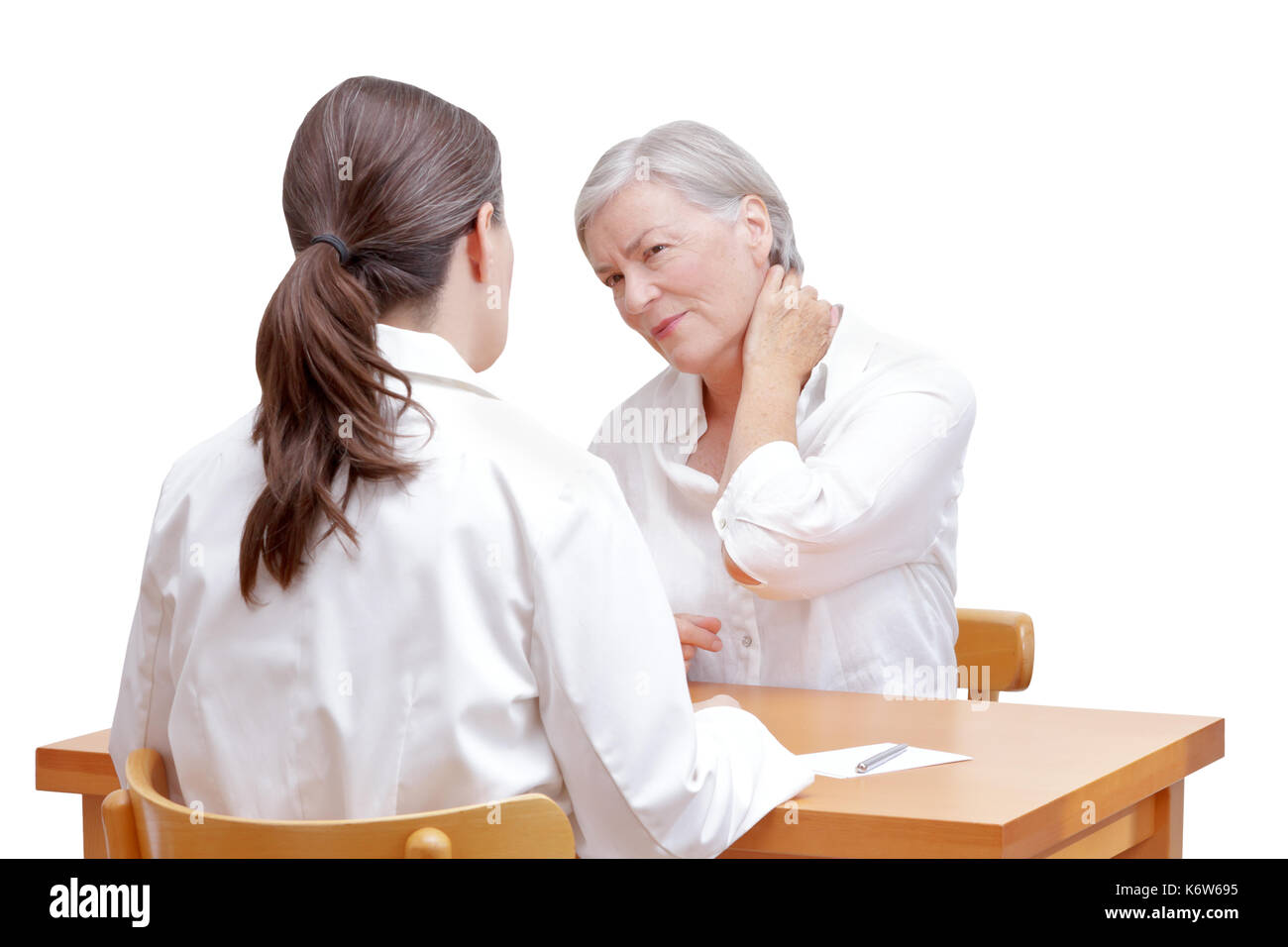 Senior female patient consulting her physician or doctor on account of acute neck pain caused by muscular tension, isolated on white background Stock Photo