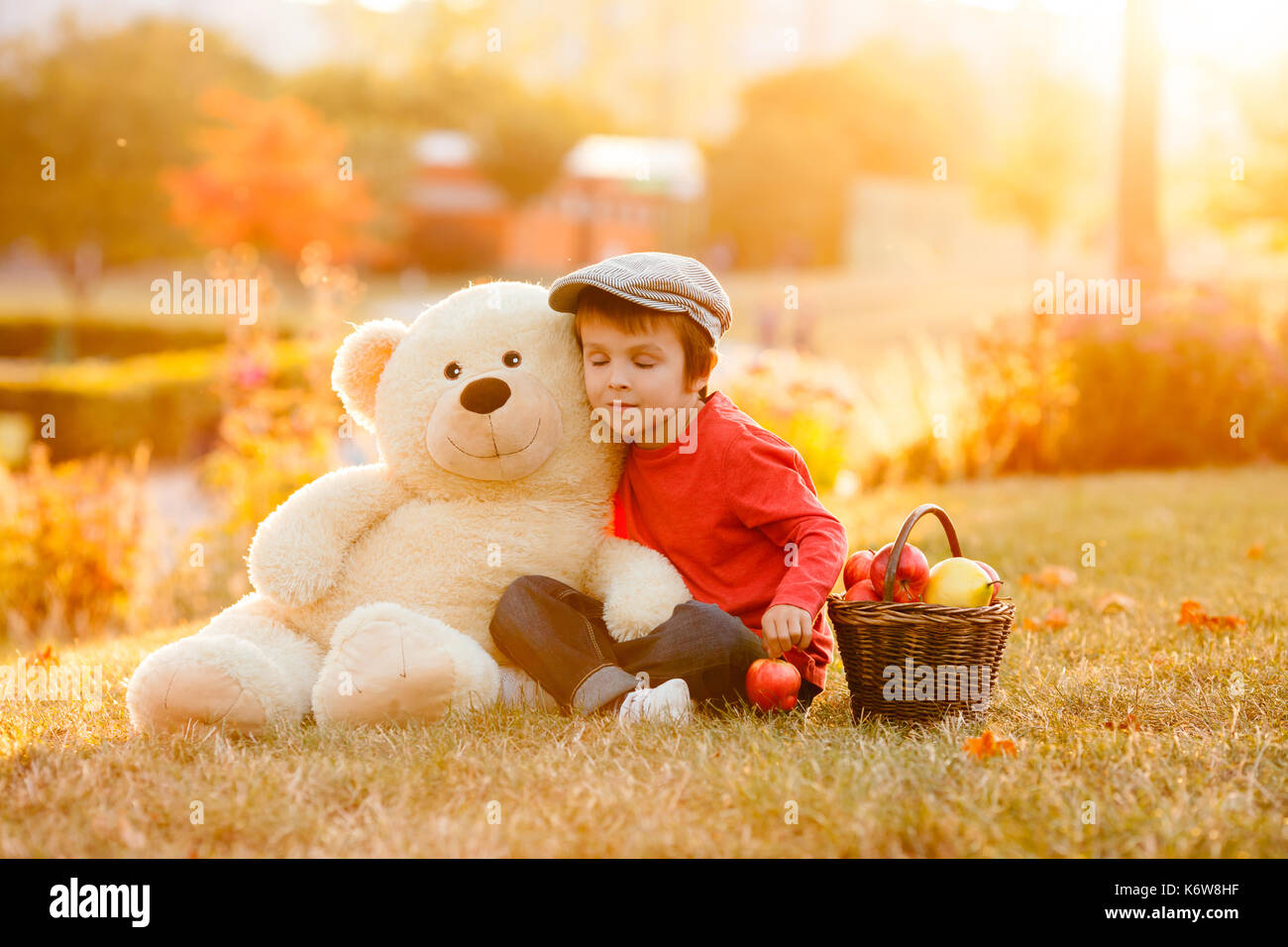 Adorable little boy with his teddy bear friend in the park on sunset ...