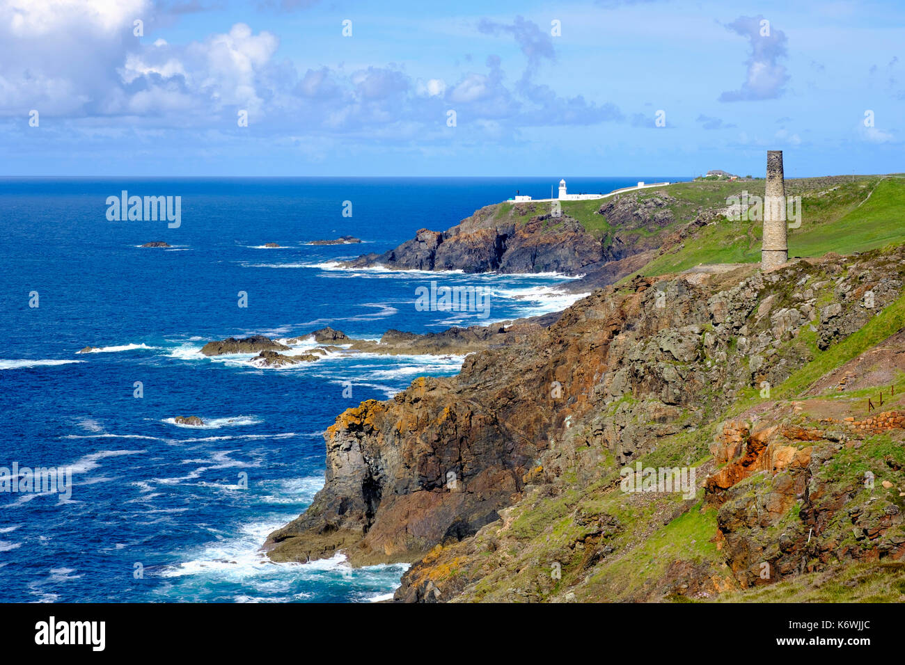 Rocky coast with old chimney from the Levant Mine and Pendeen Lighthouse, St Just in Penwith, Cornwall, England, Great Britain Stock Photo
