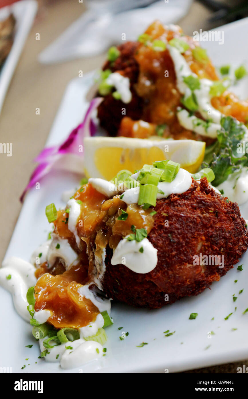 Two Gourmet Crab Cakes Topped With Sour Cream and Chives at a Fancy Sea Food Restaurant . Stock Photo