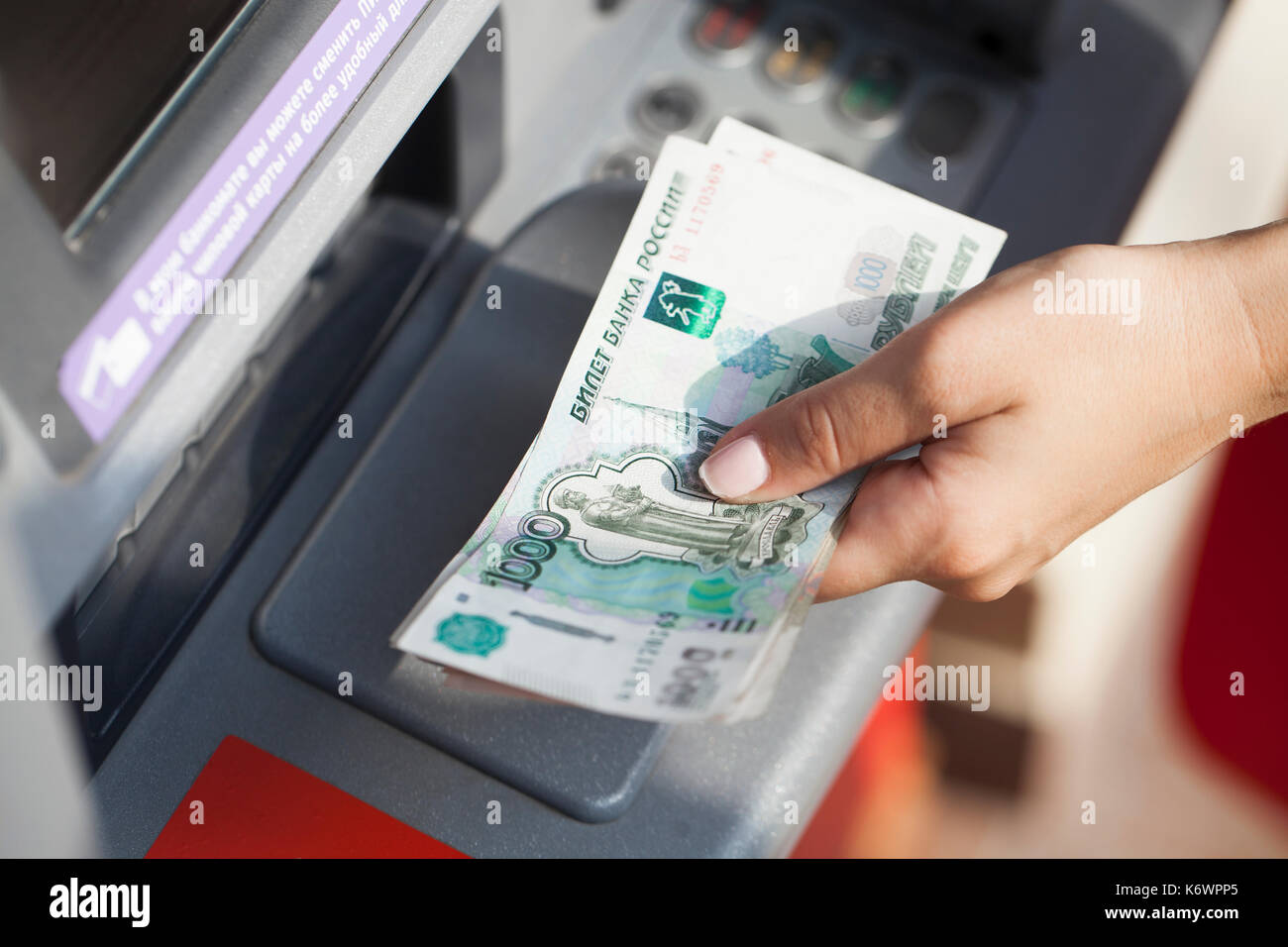 Russian rubles cash. Repayment on credit. Woman hand withdrawing money from outdoor bank ATM Stock Photo