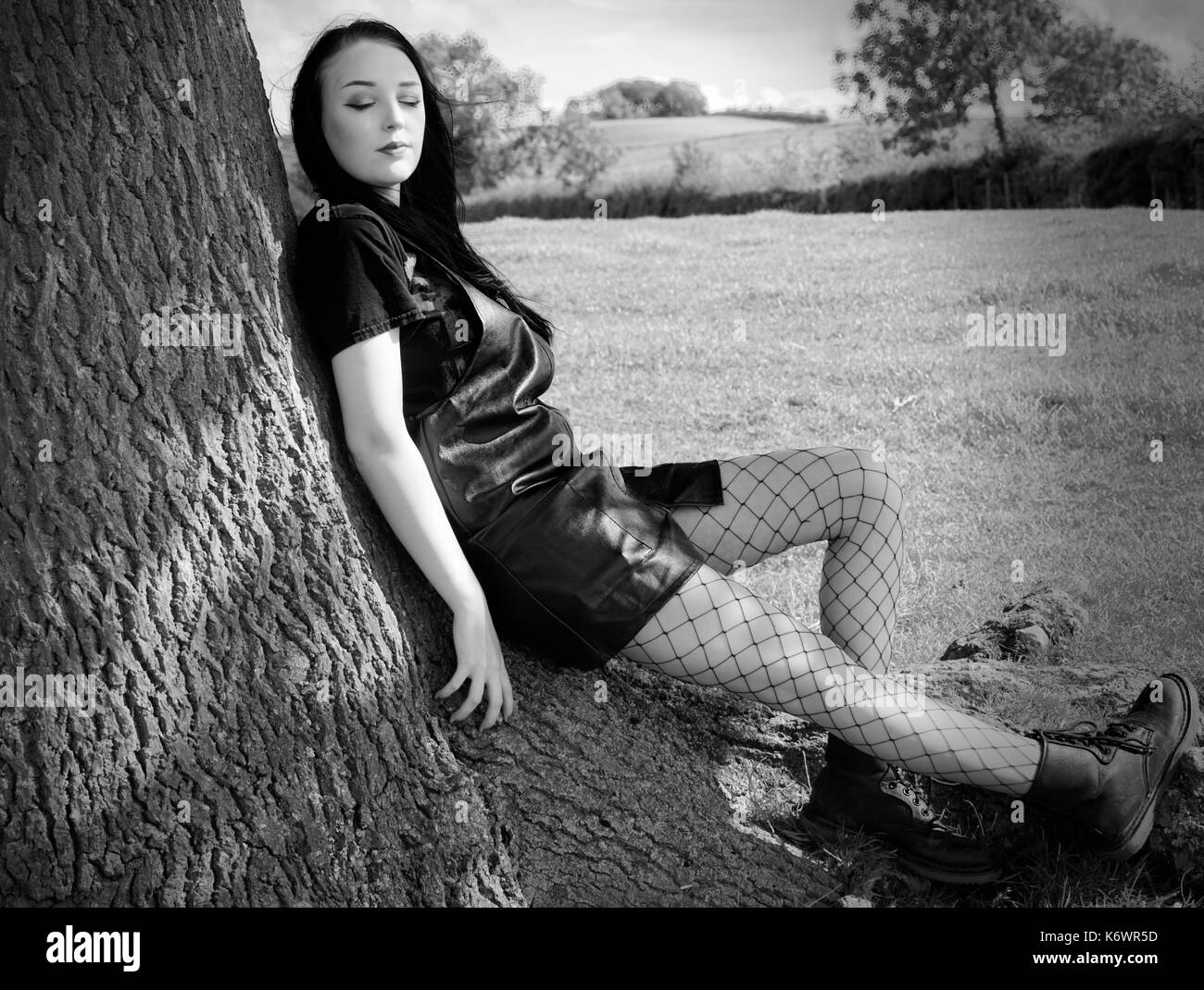a teenage girl relaxing against a tree Stock Photo