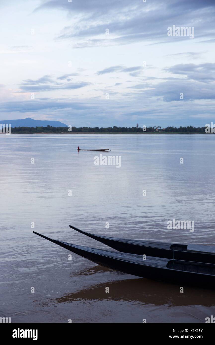 Laos, Champassak, end of canoe in front of a fisherman canoe in the middle of the Mekong in front of a green bank for sunset Stock Photo