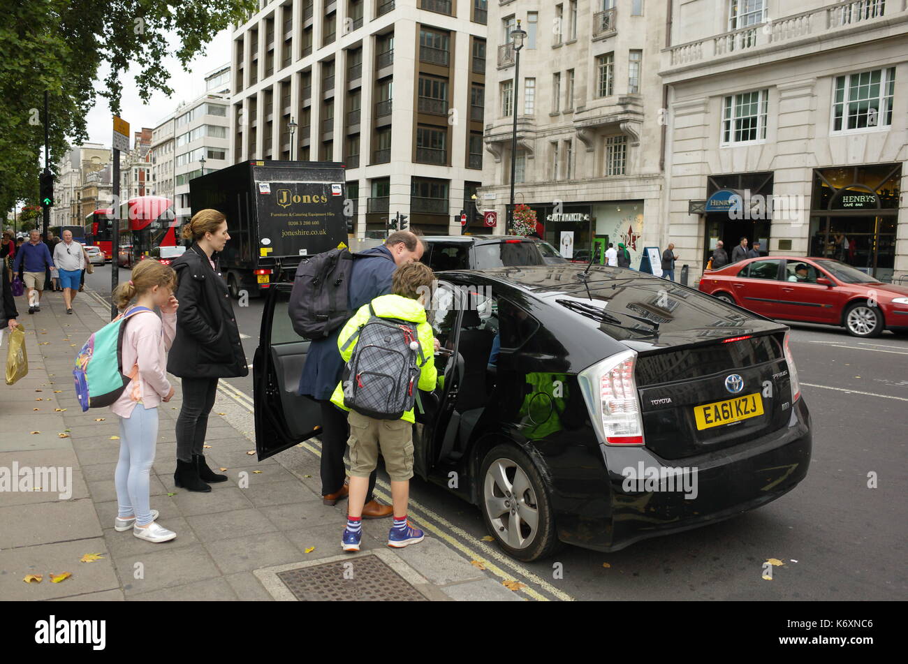 Couple with children getting into a private cab in London, UK Stock Photo