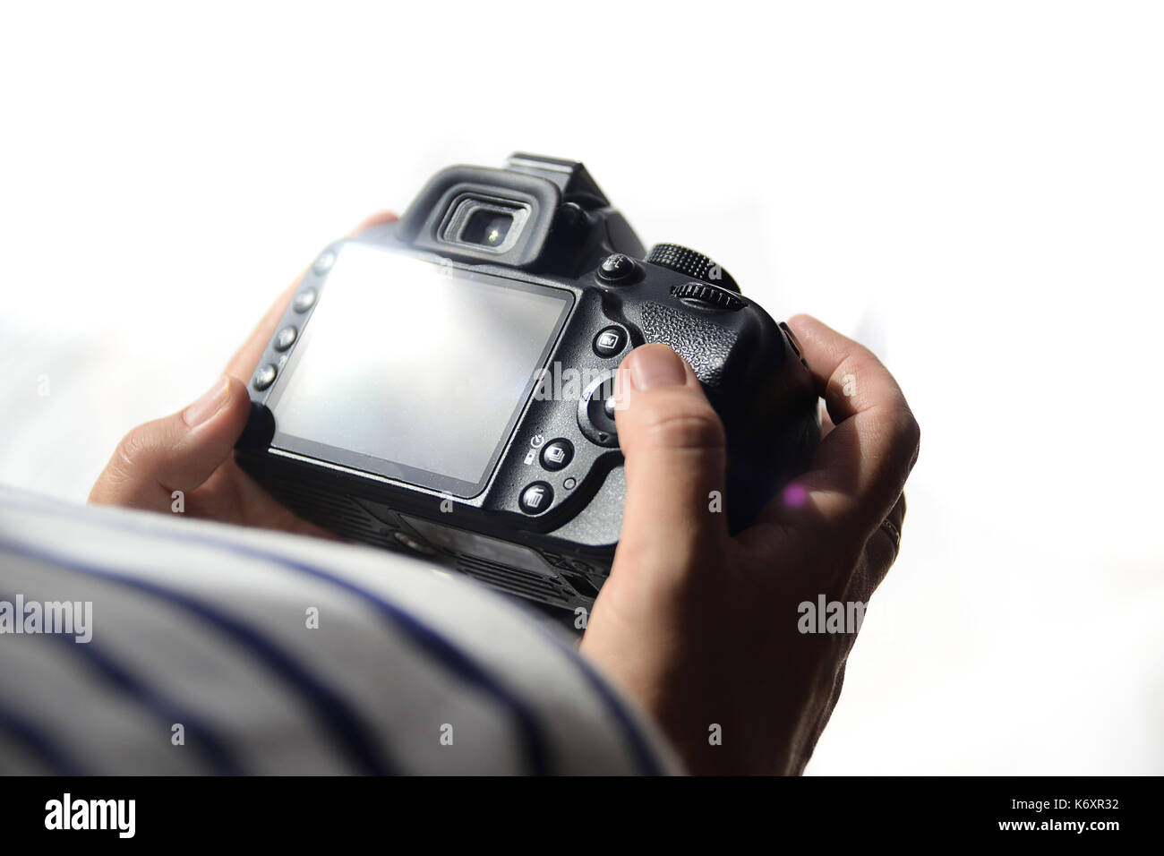Woman photographer holding a digital camera reviewing the work. White ...
