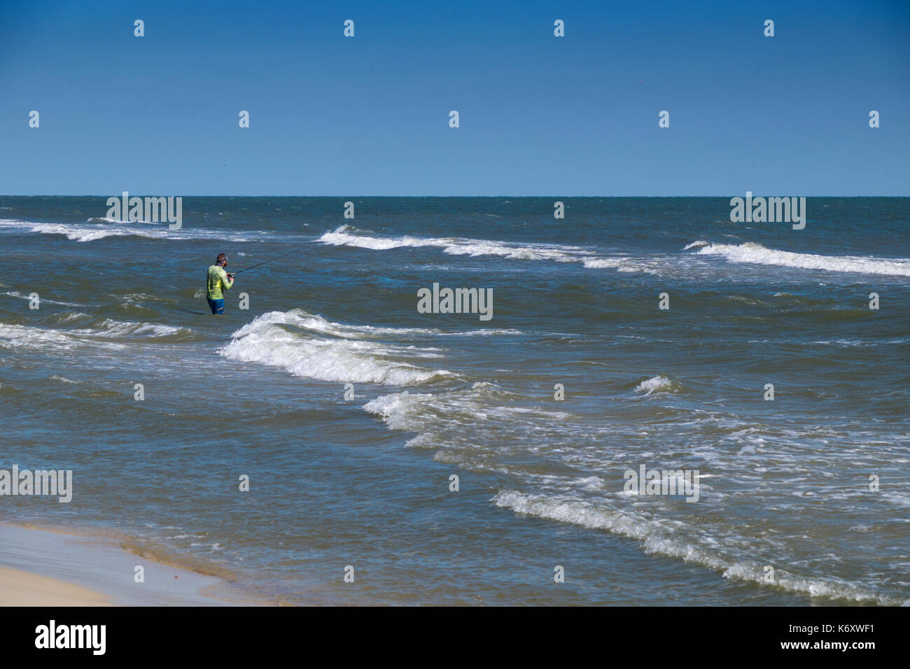 Lone fisherman surf casting in the Gulf of Mexico near Gulf Shores, Alabama. Stock Photo