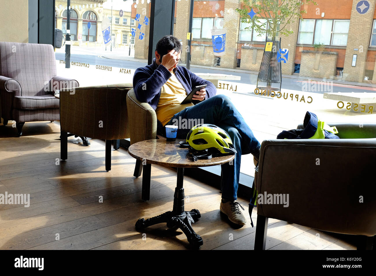 young male person sitting in cafe using computer tablet Stock Photo