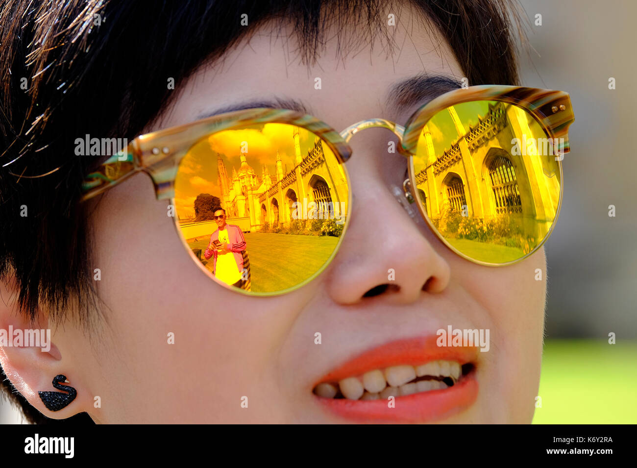 female person wearing tinted yellow sunglasses with reflection of king's college, cambridge university, england Stock Photo