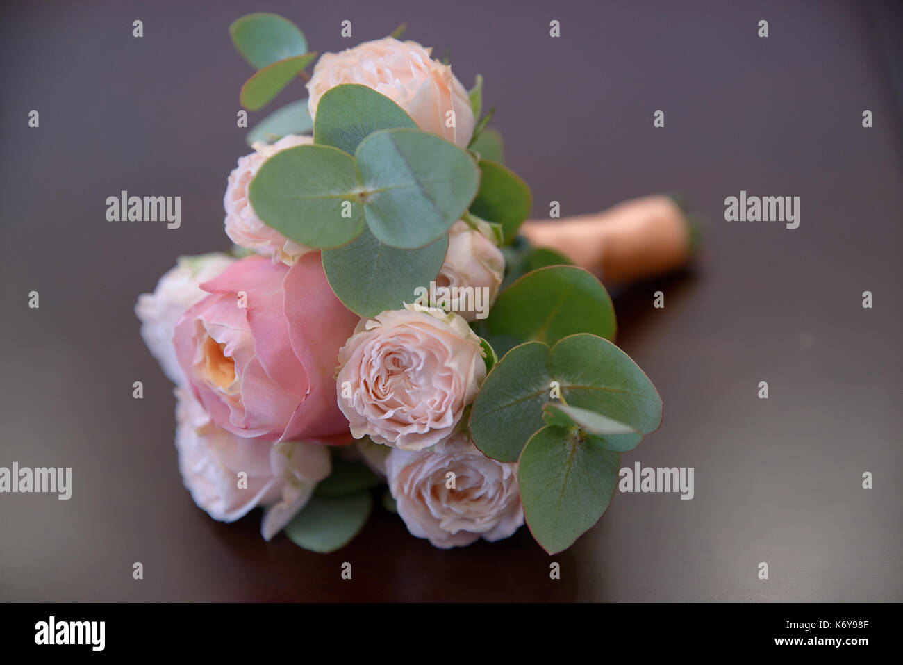 Horizontal shot of glamorous wedding bouquet featuring pink peonies and greenery against mauve background Stock Photo