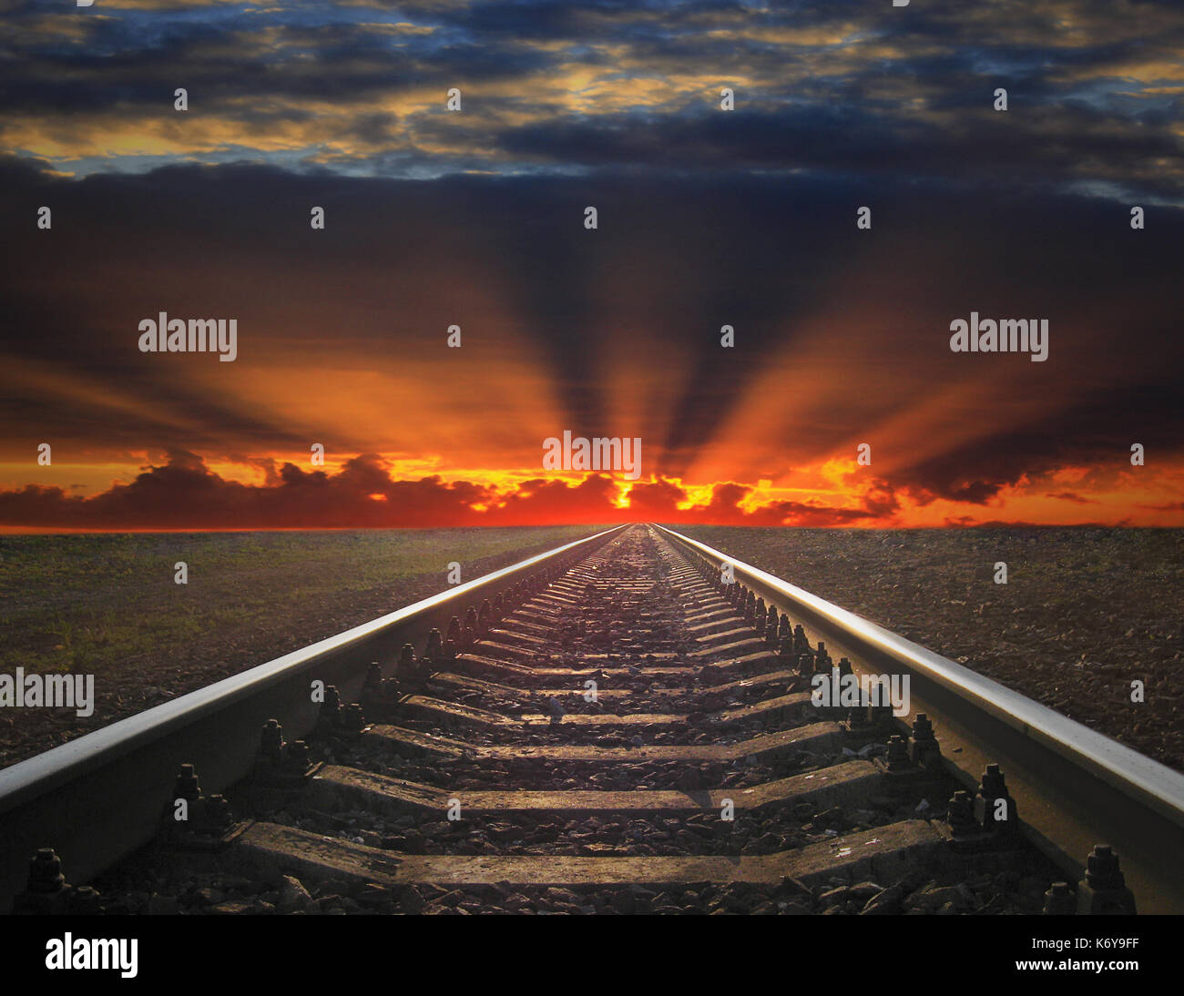 rails going away into the fiery red sunset. rails going away into the dark landscape with fiery red sunset Stock Photo