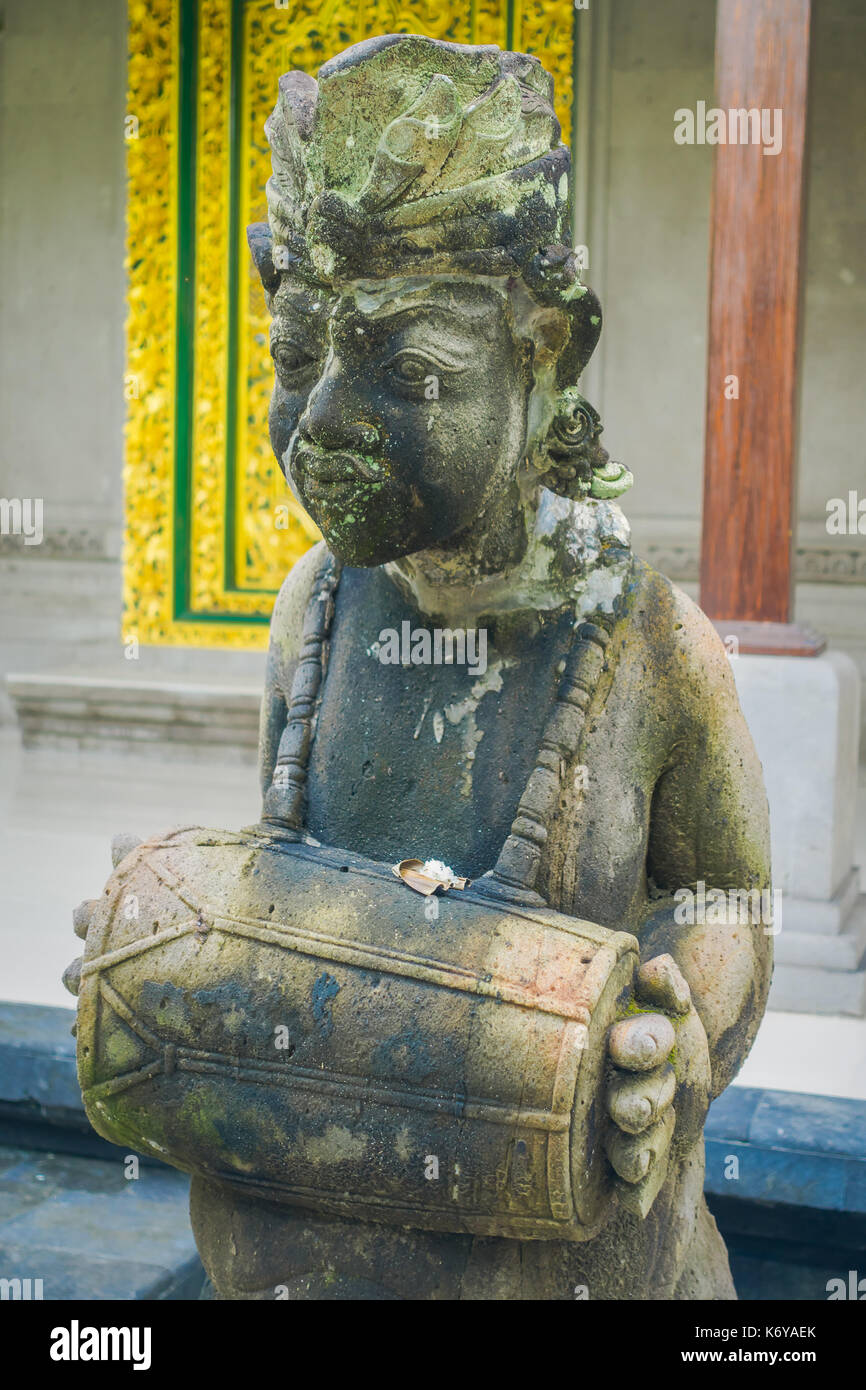 BALI, INDONESIA - MARCH 08, 2017: Stone statue holding a drum in the city of Denpasar in Bali, Indonesia Stock Photo