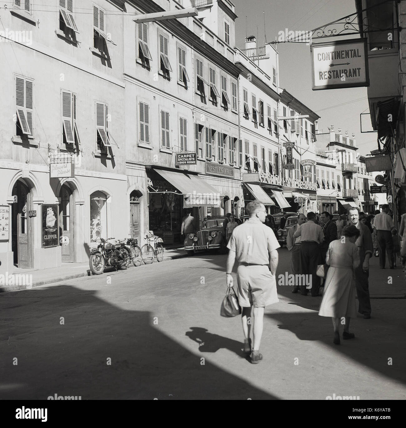 1950s, historical picture of a street in Gibraltar showing general activity, local people, shoppers etc, with the offices of Nestle and the Victoria Hotel in the distance. Stock Photo