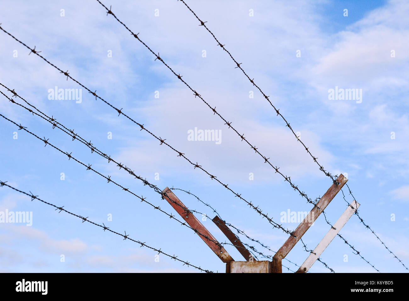 Fence of barbed wire against blue sky with clouds Stock Photo - Alamy