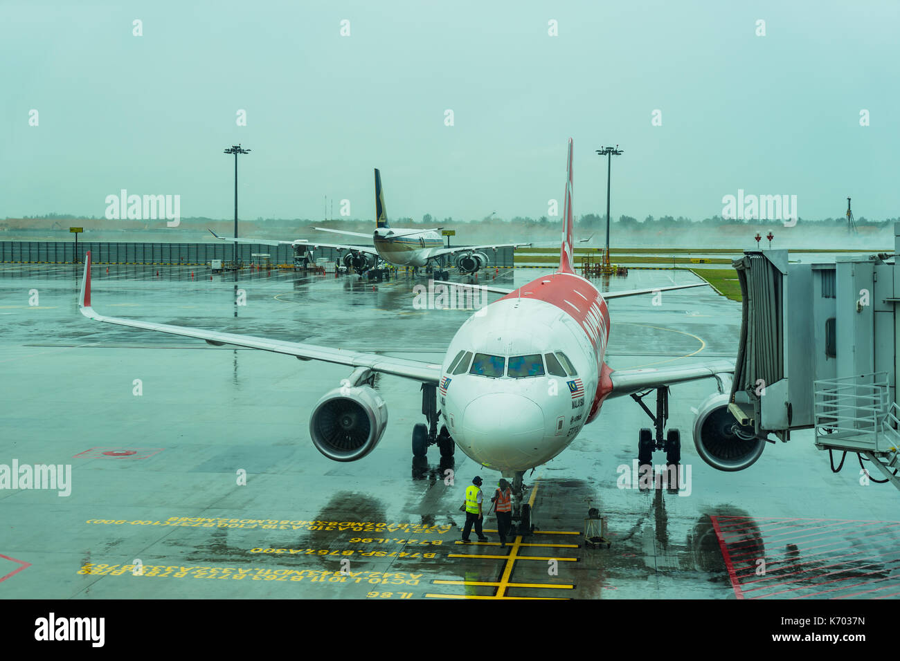 Singapore - August 12, 2017: Changi Airport Jetway for boarding passengers attached to the airplane in the raining day, an airplane stationary at airp Stock Photo