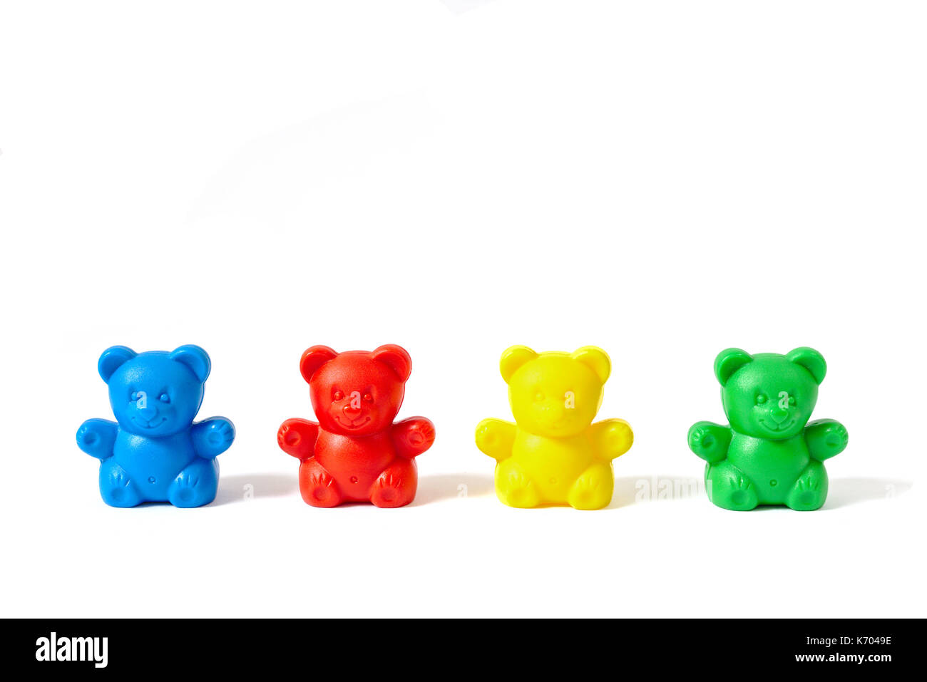 Small blue, red, yellow and green plastic toy bears isolated on white background Stock Photo
