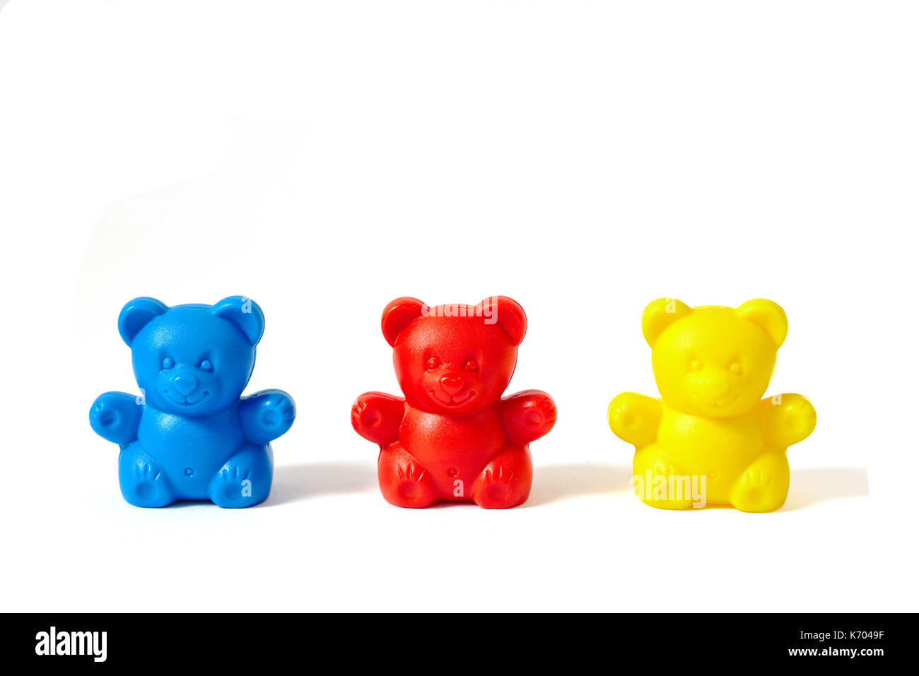 Small blue, red and yellow plastic toy bears isolated on white background Stock Photo