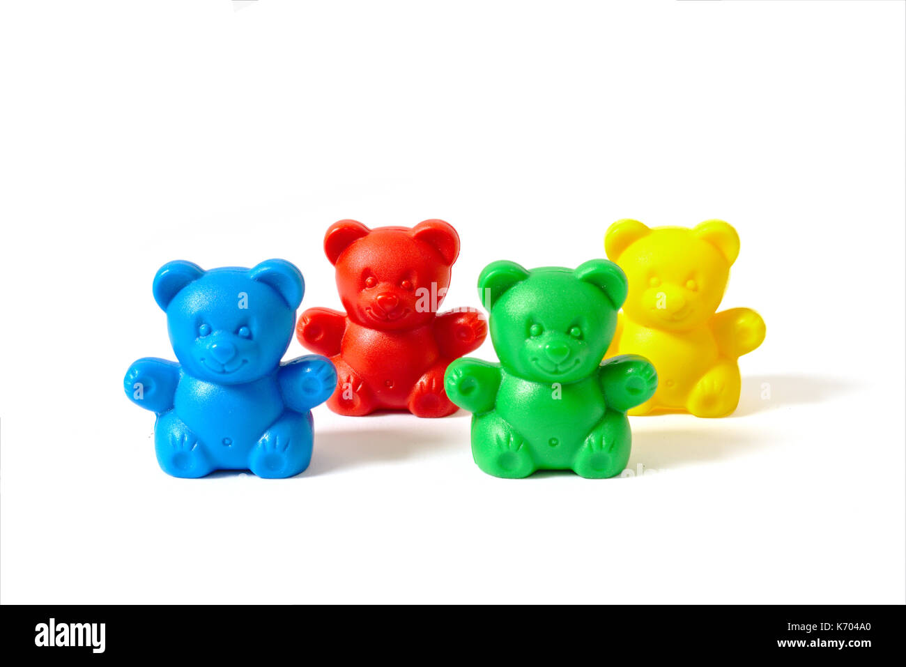 Small blue, red, yellow and green plastic toy bears isolated on white background arranged in two rows Stock Photo