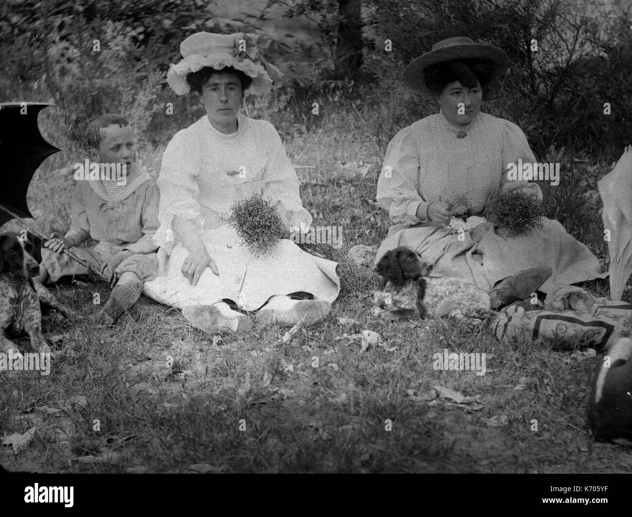 AJAXNETPHOTO. 1891-1910 (APPROX). FRANCE. - TWO LADIES EACH HOLDING A BUNCH OF FLOWERS AND DRESSED IN SUMMER DRESSES WITH HATS, A CHILD WITH AN UMBRELLA AND A DOG IN A COUNTRY LANDSCAPE. PHOTOGRAPHER:UNKNOWN © DIGITAL IMAGE COPYRIGHT AJAX VINTAGE PICTURE LIBRARY SOURCE: AJAX VINTAGE PICTURE LIBRARY COLLECTION REF:AVL FRA 1890 B29X1228 Stock Photo