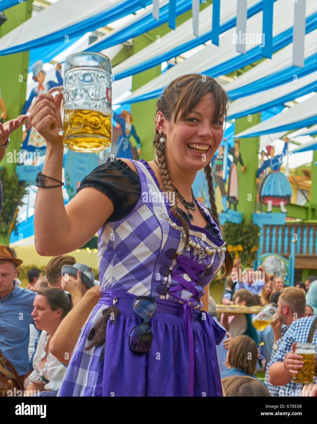 a german girl holding beer on hands in the tent of Octoberfest in Munich, Germany Stock Photo