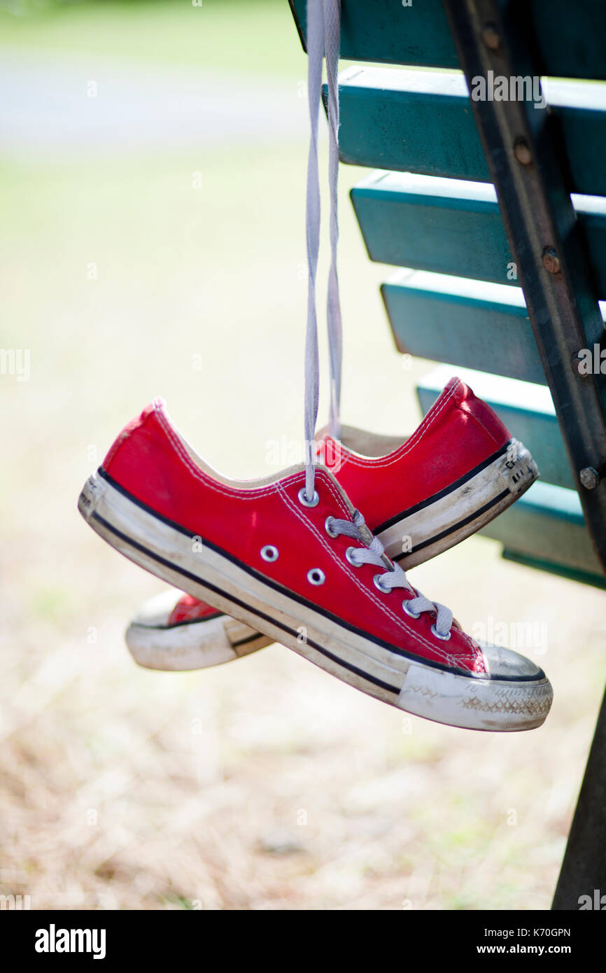 RED CONVERSE ALL STAR USED HANGING FROM A BENCH Stock Photo - Alamy