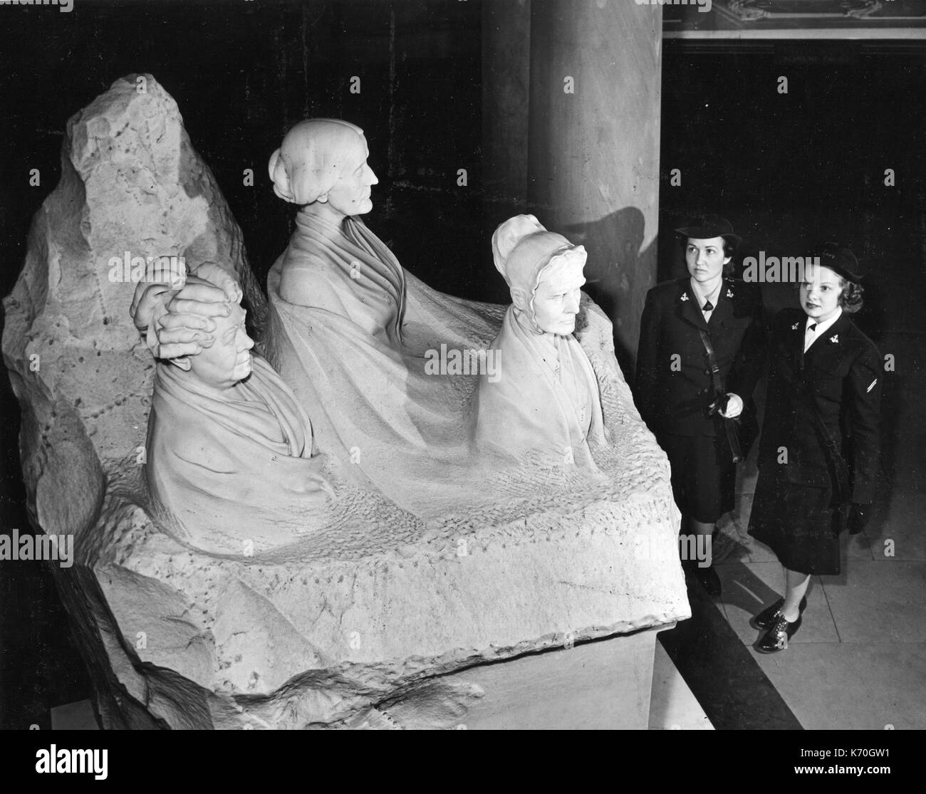 In the crypt below the Rotunda of the US Capitol is this 8-ton statue - a tribute to three American women's rights leaders, Elizabeth Cady Stanton, Susan B. Anthony and Lucretia Mott. Executed by Adelaide Johnson, the figure in the left corner was left unfinished to convey the old adage that 'woman's work is never done.' Here, two WAVES, typifying the American women of today, gaze at the three pioneers. 1945, Washington, DC. Stock Photo