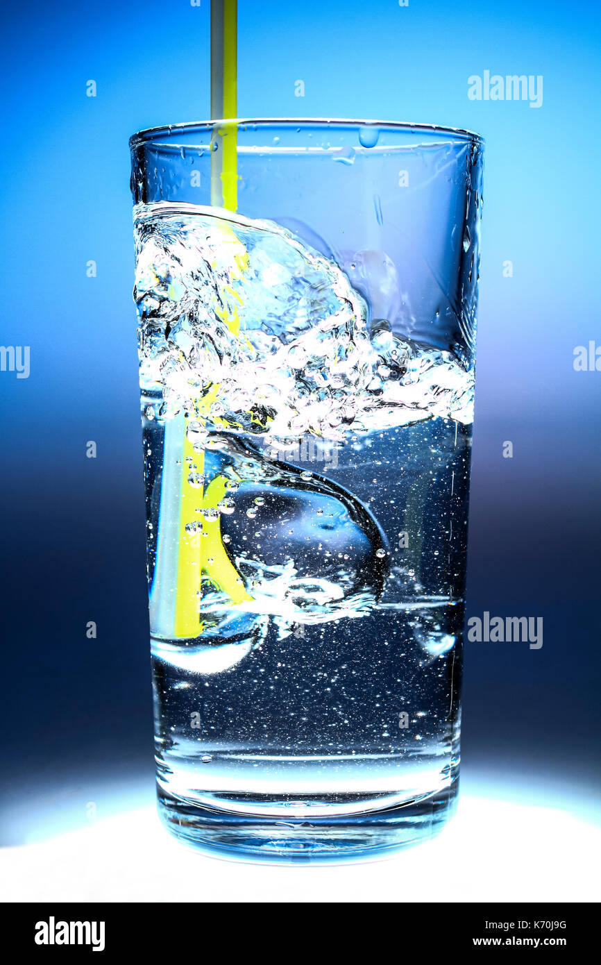 Cool refreshing glass of drinking water with a straw and bubbles