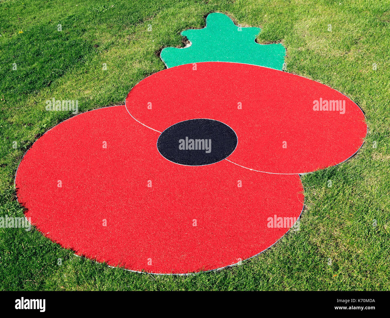Remembrance Day Poppy, logo, symbol, set in turf, lawn, grass, Hunstanton, Norfolk, England, UK, war memorial, memorials, emblem Stock Photo