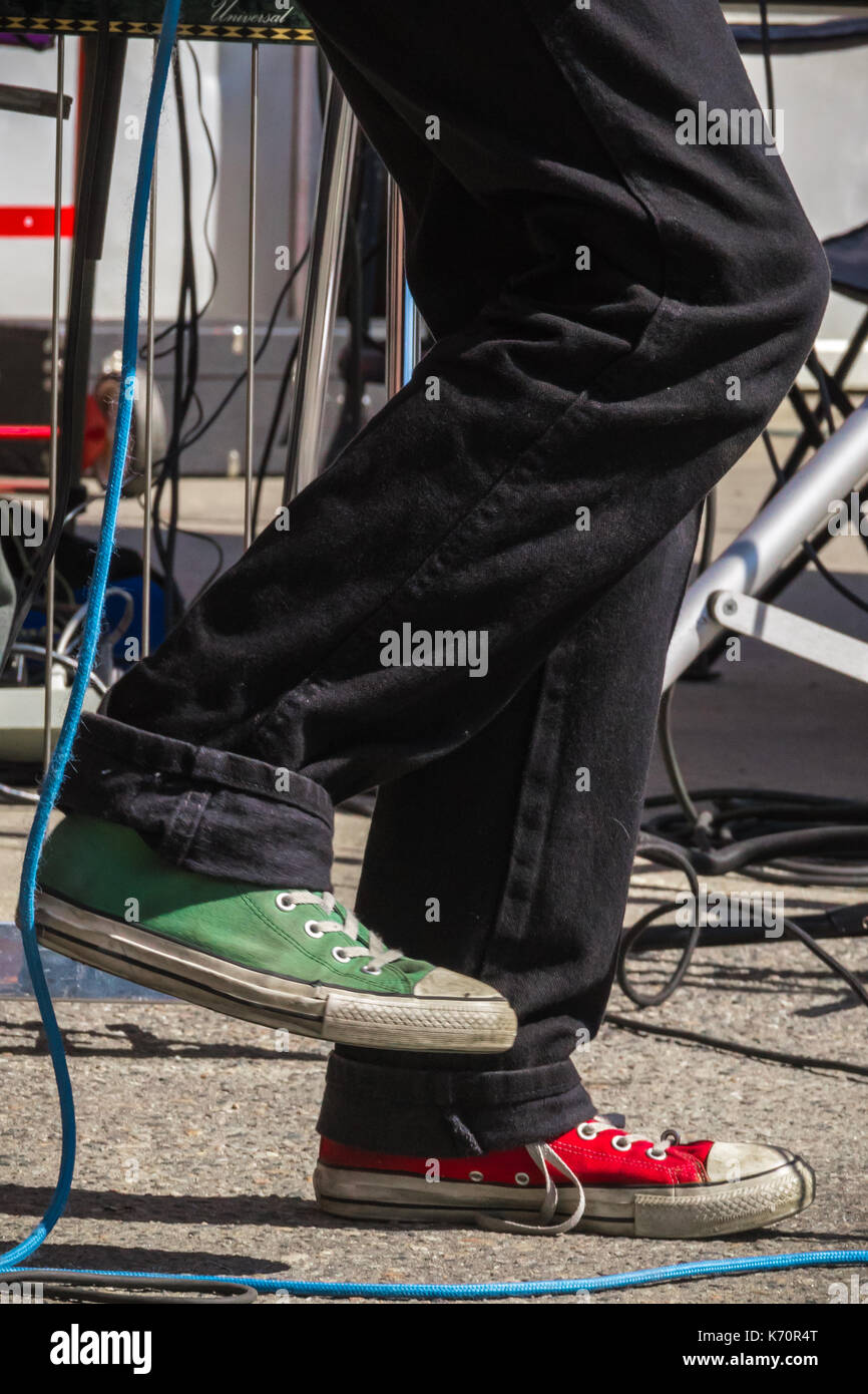A rock musician with mismatched red and green sneakers performs at an outdoor local music festival in Keene, NH. Stock Photo