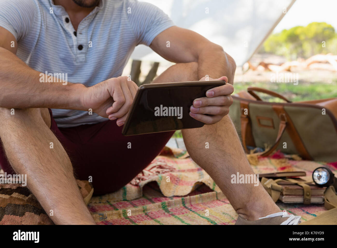 Mid section of man using tablet while sitting in tent Stock Photo