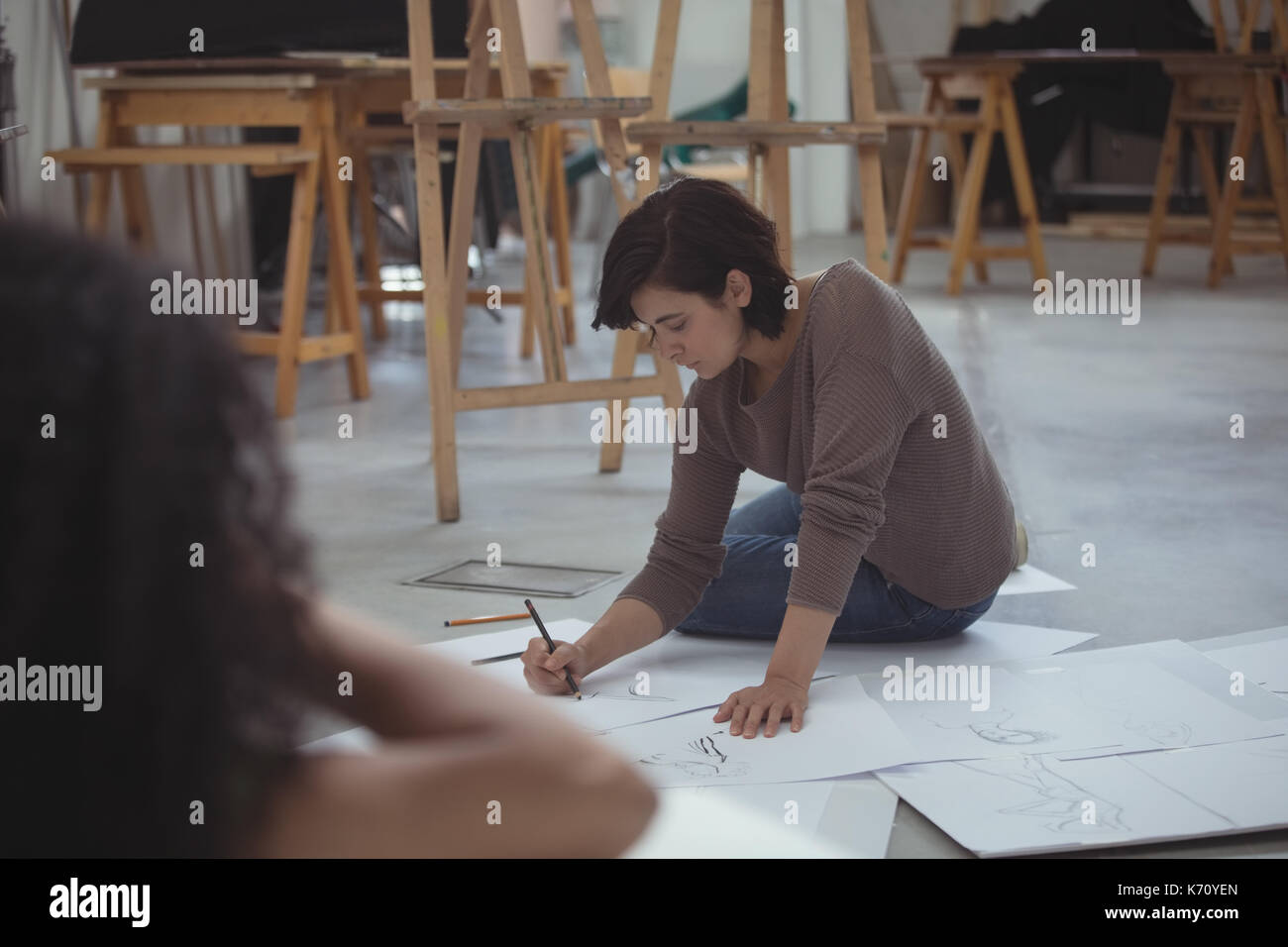 Female artist drawing a sketch of woman on paper in art studio Stock ...