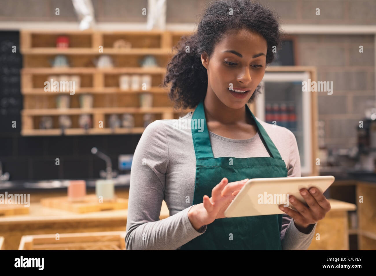 Smiling beautiful waitress using digital tablet in cafÃƒÂ© Stock Photo