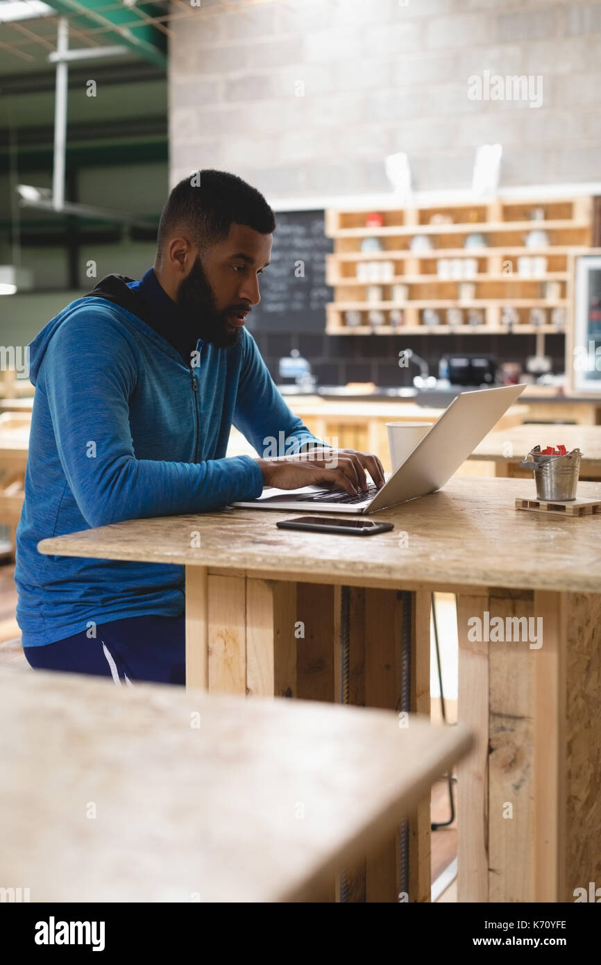 Young man using laptop while sitting at table in coffee shop Stock Photo