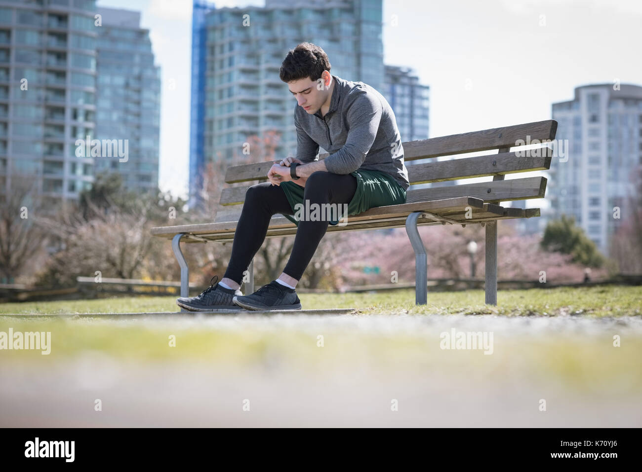 Surface level of young man checking time while sitting on bench at park ...