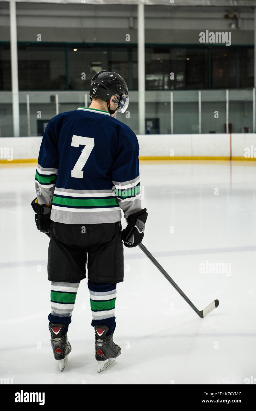 Rear view full length of male player with ice hockey stick at rink