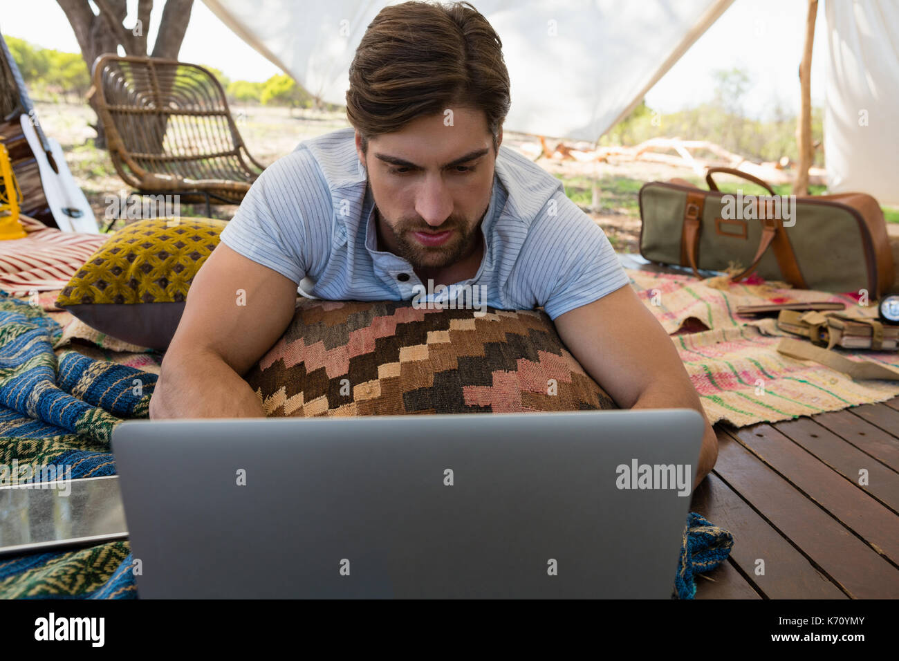 Relaxed young man using laptop while lying down in tent Stock Photo