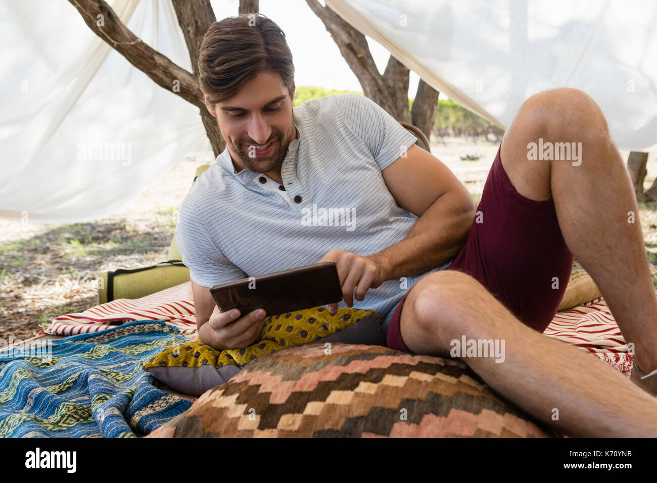 Relaxed young man using digital tablet in tent Stock Photo