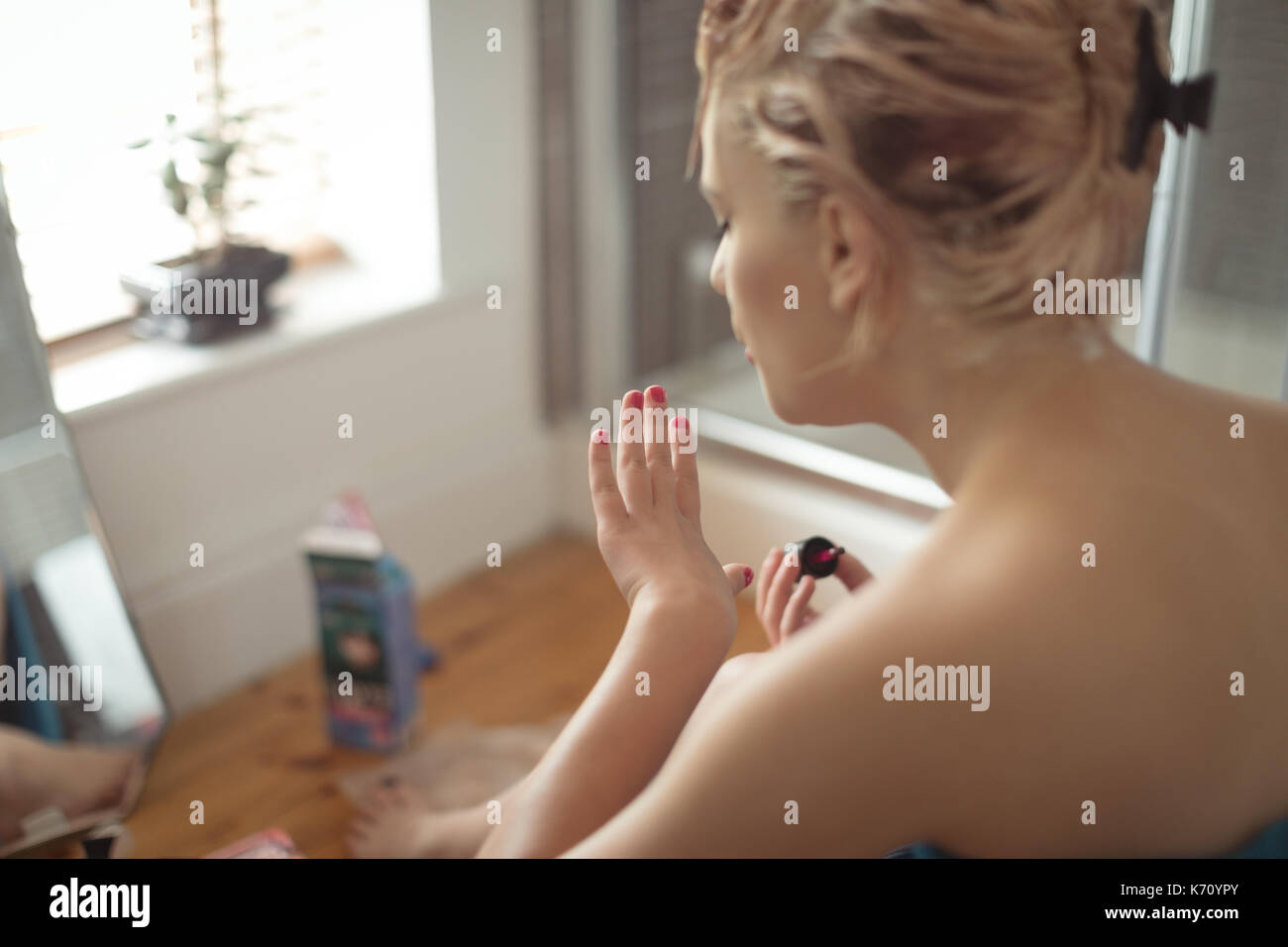 Young woman looking at fingernails in bathroom at home Stock Photo