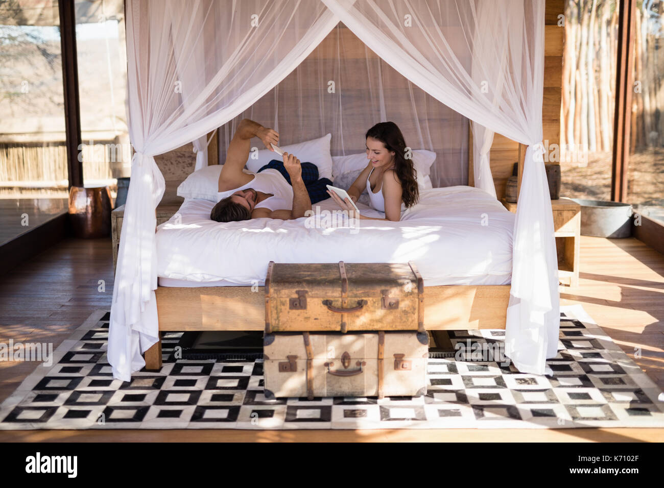 Smiling couple using digital tablet on bed in cottage Stock Photo