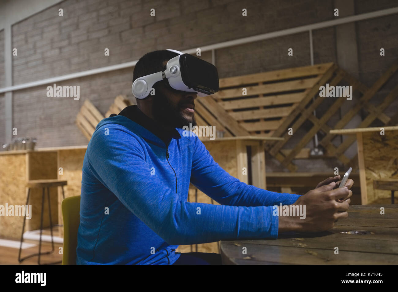 Man using mobile phone while looking through virtual reality in cafeteria Stock Photo