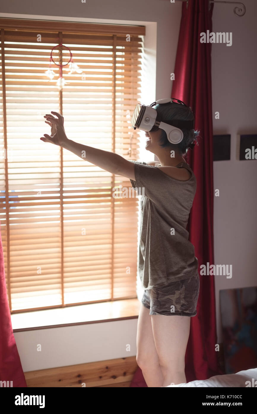 Young woman using virtual reality simulator by window at home Stock Photo