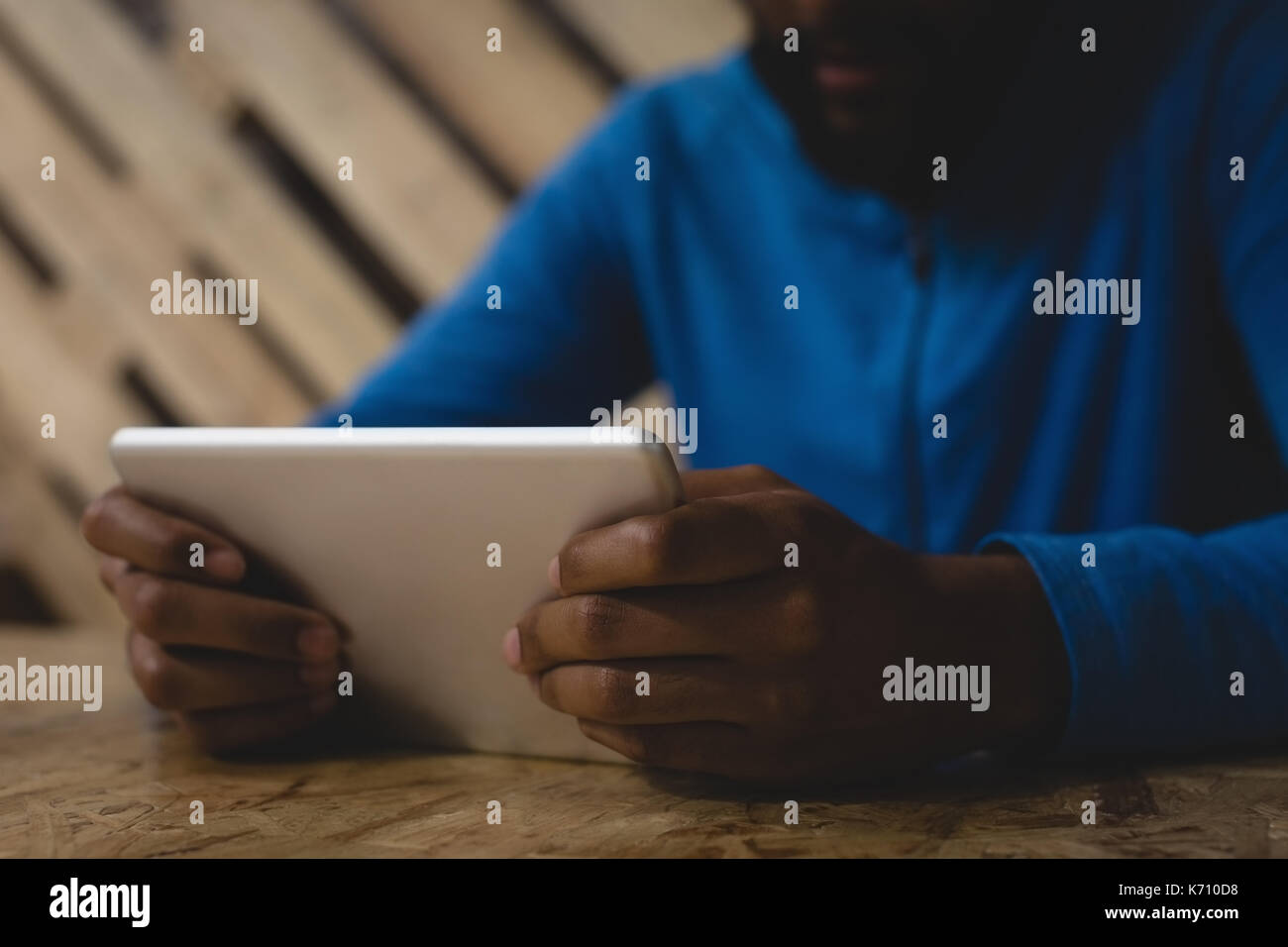 Midsection of man using digital tablet while sitting at table in cafe Stock Photo