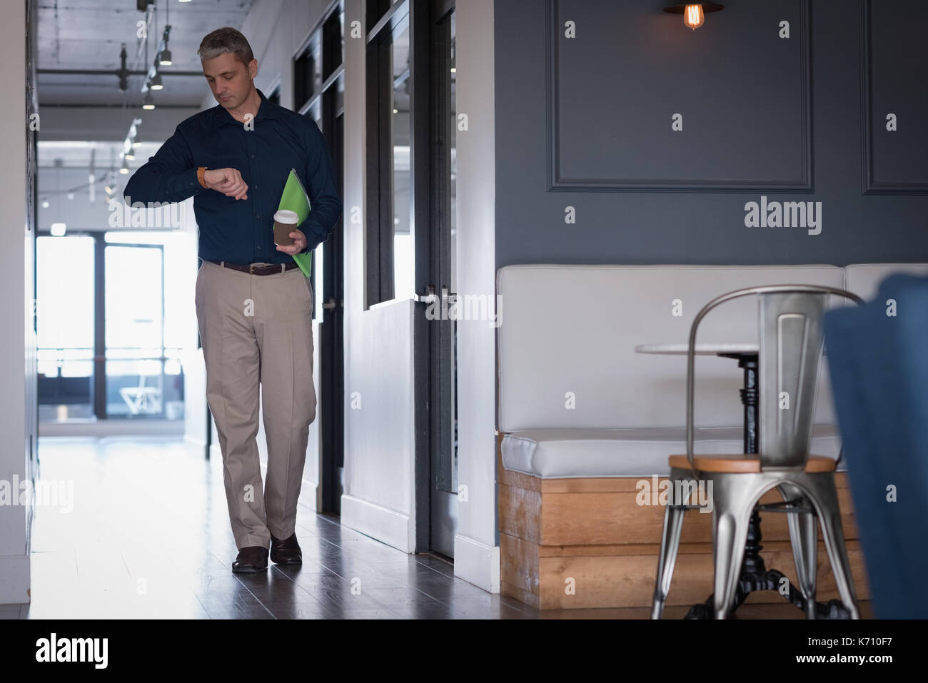 Businessman checking time while walking in corridor at office Stock Photo