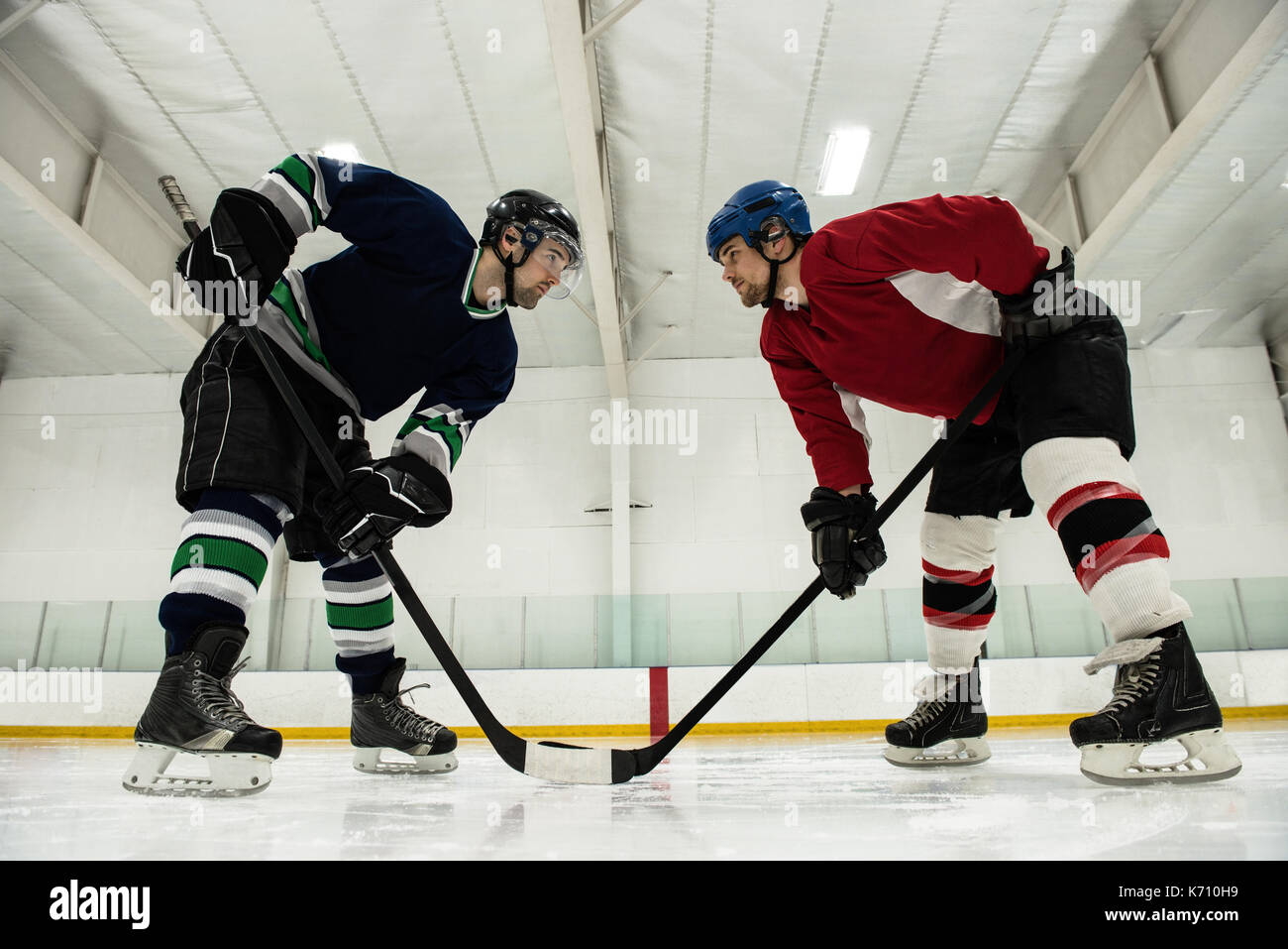 Full length of male ice hockey players looking face to face at rink